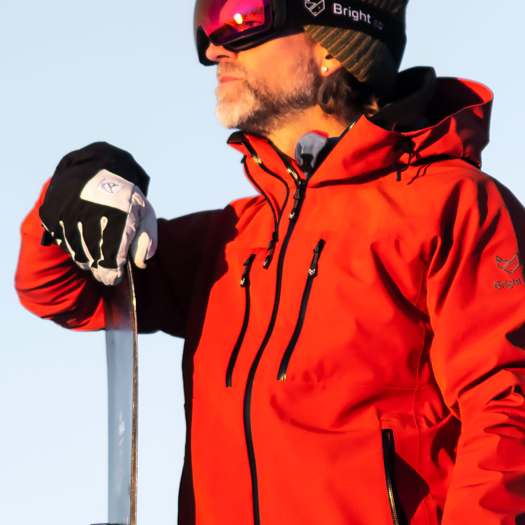 Man med snowboard i röd skaljacka från Bright Equipment.